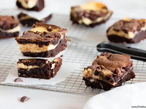 Schokoladige cheesecake brownies mit cremiger Füllung und Schokostückchen, gestapelt auf einem Gitter.