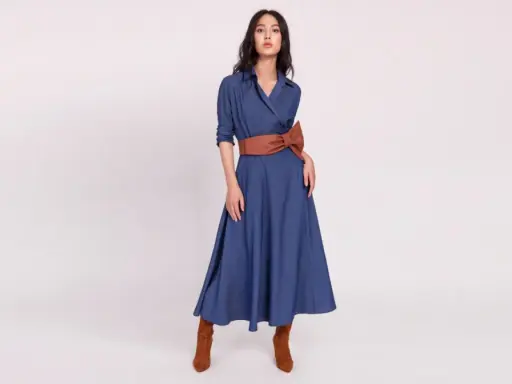 Modelka w niebieskiej sukience z brązowym pasem i botkami. Brązowy to kolor, jaki pasuje do niebieskiego, tworząc elegancką stylizację.