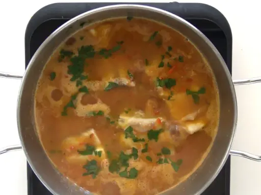 Guiso de corvina burbujeante con perejil picado, listo para servir. ¡Perfecto para tus recetas de corvina guisada!