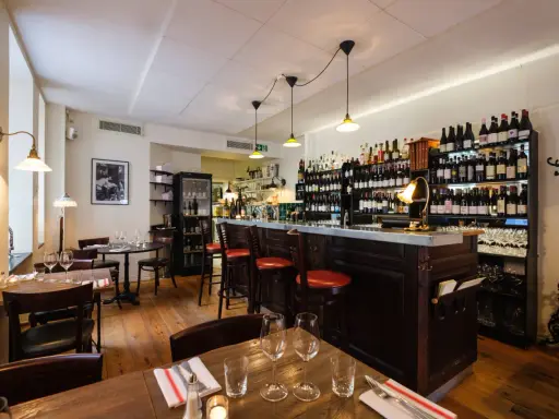 Mysig vinbar med trägolv, bardisk och hyllor fyllda med flaskor. Perfekt för att läsa bouchon recensioner över ett glas vin.