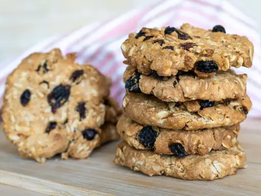 Una pila di biscotti integrali con uvetta e mandorle, perfetti biscotti senza zucchero per una pausa sana.
