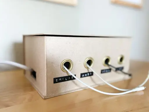 Kreative ladekabel aufbewahrung selber machen aus einem Karton. Kabel sind ordentlich durch Ösen geführt und beschriftet.