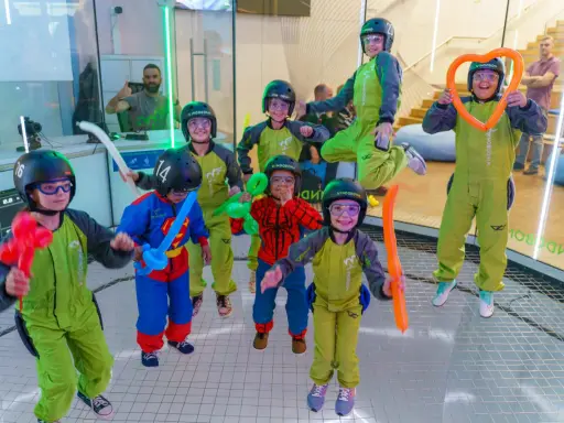 ¡Diversión volando en Madrid! Niños con trajes verdes y cascos disfrutan de la experiencia, algunos con globos. ¡Un fin de semana inolvidable!