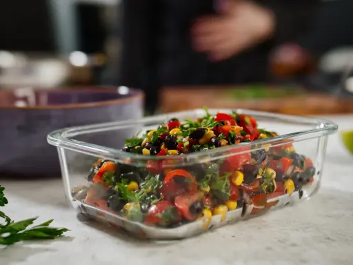 Frischer schwarze bohnen salat mit Mais, Tomaten und Kräutern in einer Glasbox.