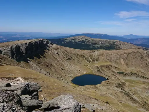 Paisaje montañoso con un lago azul en un valle, ideal para senderismo Soria.