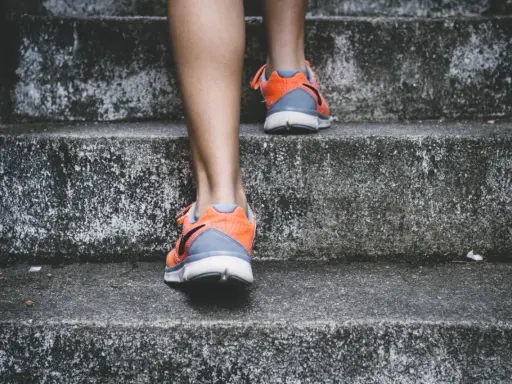 Pomarańczowe buty sportowe na siłownię, idealne na trening, wspinają się po betonowych schodach.
