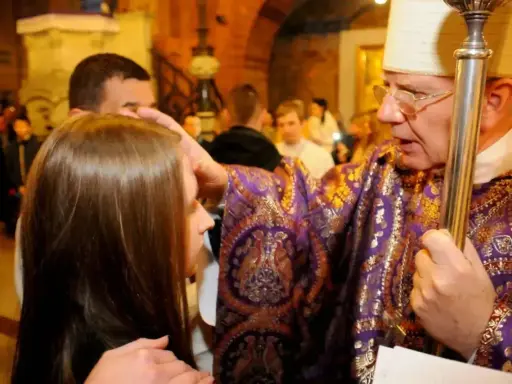 Biskup namaszcza czoło dziewczyny podczas bierzmowania. Czy bierzmowanie jest obowiązkowe? To ważny sakrament.