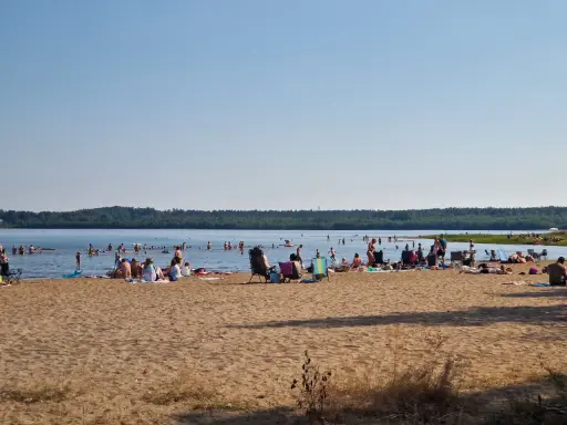 Folk njuter av solen och badar vid en strand, en perfekt plats för camping i Luleå.