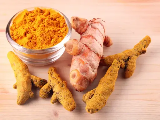 Racines de curcuma fraîches et en poudre, symboles des nombreux curcuma bienfait pour la santé.