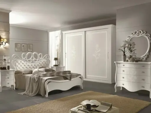 Elegante camera da letto bianca con letto capitonné, armadio scorrevole e comò con specchio. Ottime idee camera da letto bianca per un ambiente raffinato.