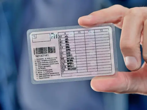 Prawo jazdy w dłoni, symbol wolności i odpowiedzialności. Ważność dokumentu to klucz do swobodnego poruszania się.
