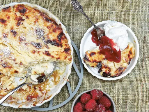 En gyllene falsk ostkaka med krispiga kanter, serverad med vispad grädde, sylt och färska hallon.