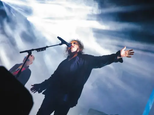 Robert Smith sjunger med utsträckta armar under The Cure i Stockholm.