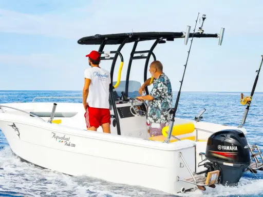 Deux hommes sur un bateau de pêche, avec un roll bar pour bateau, profitent de la mer bleue.