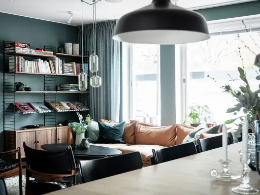 Vardagsrum med bokhylla i 50-talsstil, soffa i läder och stora fönster.
