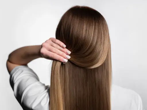 Capelli lisci e setosi, senza crespo, grazie a una routine efficace. La mano accarezza la chioma lucente.