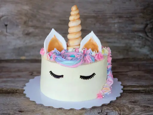 Ein magischer einhorn kuchen mit pastellfarbener Glasur, einem gedrehten Horn und süßen Wimpern.