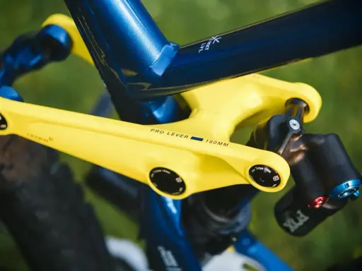 Żółte ramię przerzutki z napisem "PRO LEVER 180MM" na tle niebieskiej ramy roweru. To połączenie zapewnia doskonały reach i stack, a także wzrost wydajności.