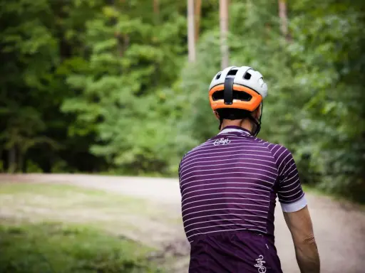 Kolarz w kasku i koszulce w paski jedzie ścieżką przez las. Idealny rower crossowy na takie wyprawy.