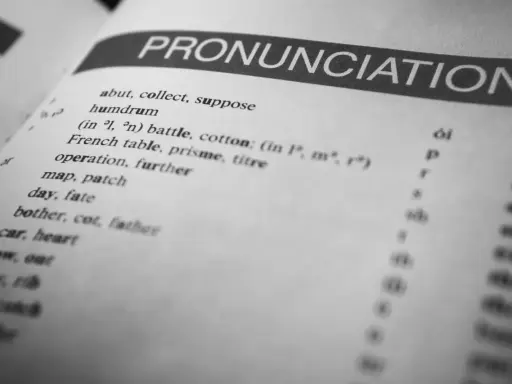 Otwarta książka z hasłem "PRONUNCIATION". Lista słów i symboli fonetycznych pokazuje, czy angielski jest trudny.