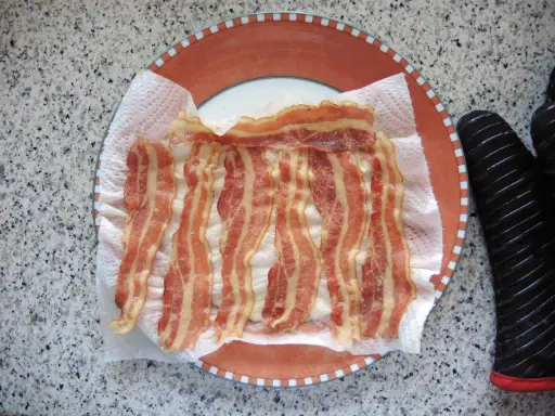 Fertig zubereitetes Bacon auf Küchenpapier auf einem Teller. Schnell und einfach in der Mikrowelle gemacht.