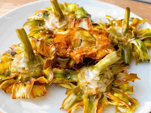 Carciofi fritti croccanti su un piatto bianco, un modo delizioso per imparare come cucinare i carciofi.