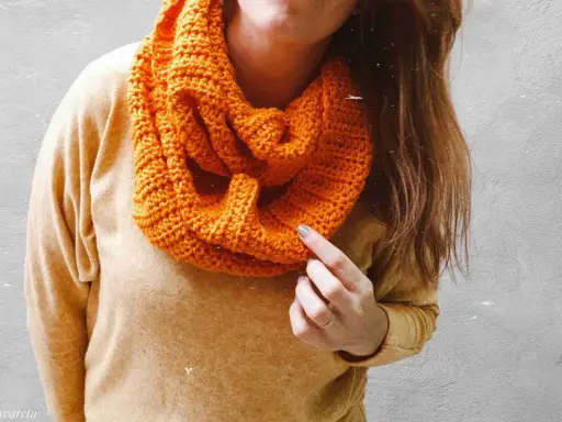Persona con una bufanda naranja tejida, lista para el frío.