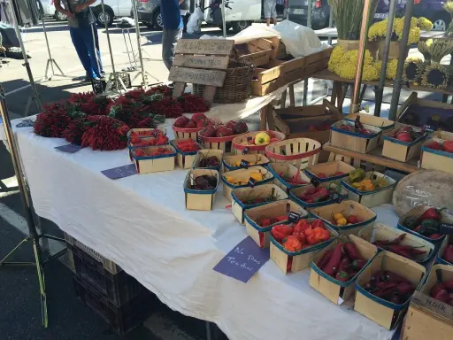 Au marché de Carpentras, des piments rouges vifs et des poivrons colorés sont présentés dans des paniers en bois.