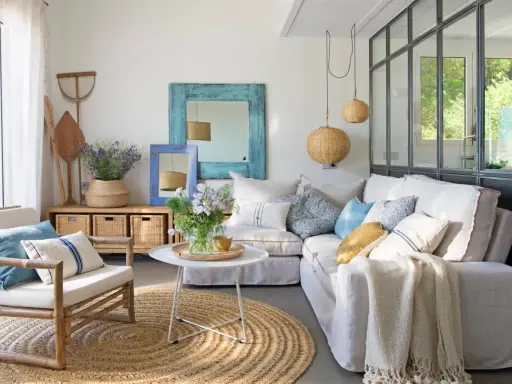 Ideas para decorar casa playa poco presupuesto: sofá blanco, alfombra de yute, cestas de mimbre y detalles marineros.
