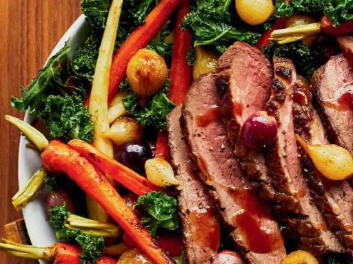 Tranches de magret de canard juteux, accompagnées de carottes rôties, d'oignons grelots et de chou frisé. Un plat savoureux et coloré.