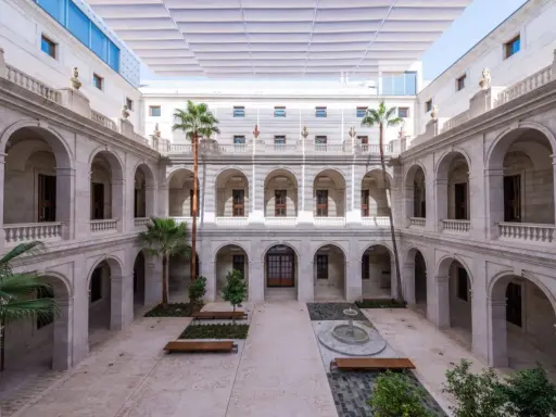 Hof des Malaga Museums mit Arkaden, Palmen und einem Brunnen.