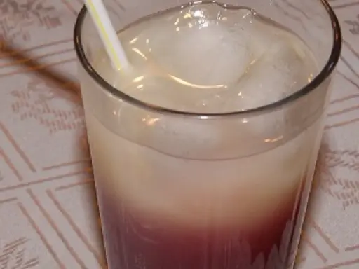 Szklanka z drinkiem z lodem i słomką, z widocznym podziałem na warstwy koloru.