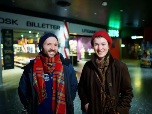 Två glada personer vid en biljettkiosk, redo att se filmer på bio nu.