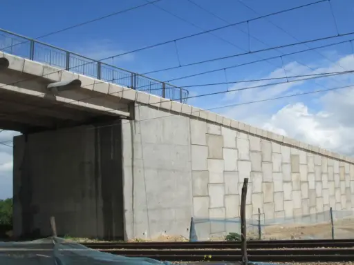 El estribo del puente de hormigón se alza imponente, sosteniendo la estructura sobre las vías del tren.