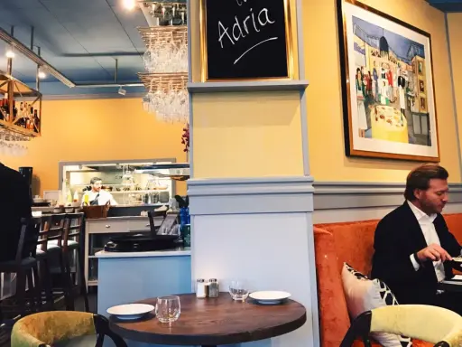 Man äter på Adria ristorante & bar. En tavla med texten "Adria" hänger på väggen.