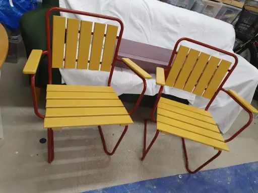 Två gula och röda **grythyttan stolar gamla modeller** står bredvid varandra.