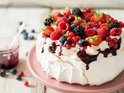Beza pavlova która zawsze wychodzi, udekorowana bitą śmietaną i mnóstwem świeżych owoców leśnych.