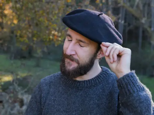 Hombre con barba ajustando su boina de lana, ideal para aprender como hacer una boina de lana.