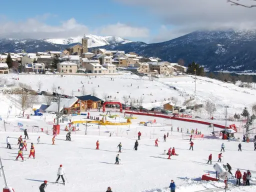 Un pueblo nevado en el Pirineo francés con niños esquiando y divirtiéndose en la nieve.