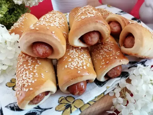 Złociste, pieczone mini hot dogi posypane sezamem, gotowe do podania. Idealne na przekąskę!