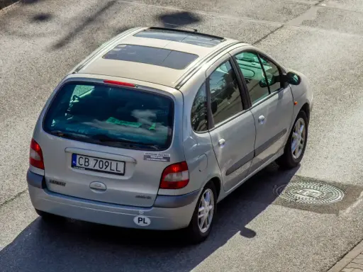 Srebrny Renault Scenic z naklejką "Ubezpieczony przez mafię". Szybkie auta i zimna noc, jak w tekstach SB MAFFIJA.