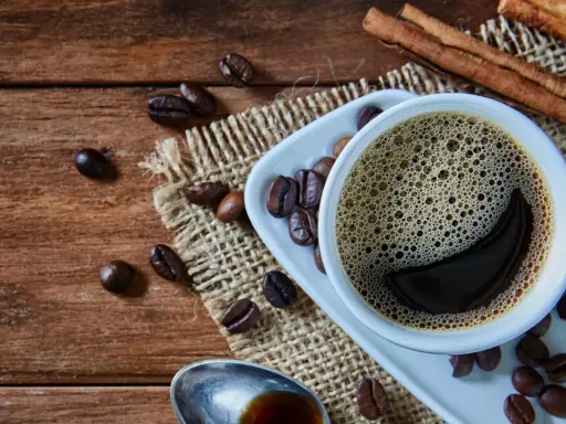 Heißer Kaffee mit Zimt, frisch zubereitet von einem Vollautomaten, duftet auf rustikalem Holz.