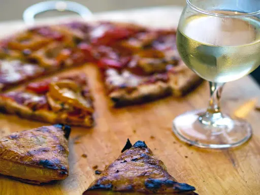 En saftig pizza med ett glas vitt vin till. Perfekt för en mysig kväll.