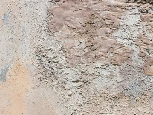 Texture d'un vieux mur dégradé, révélant des traces de salpêtre et des couches de peinture écaillée.