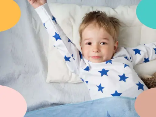 Niño de 3 años, con pijama de estrellas, estirándose en la cama.