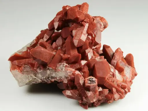 Grappolo di cristalli di quarzo rosso, con sfaccettature lucide. Il quarzo rosso significato è legato all'energia vitale e alla passione.
