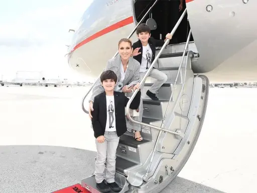 Celine Dion med sina barn på trappan till ett privatjet. Familjen ser ut att vara på väg på en resa.