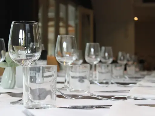 Un verre à eau et un verre à vin sont positionnés sur une table dressée, prêts pour un repas.