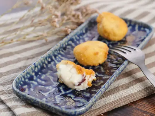 Deliciosa croqueta de jamón, cremosa por dentro y dorada por fuera, servida en un plato azul.