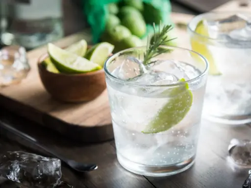 Kto pije gin z tonikiem? Orzeźwiający drink z lodem, limonką i rozmarynem, gotowy do degustacji.